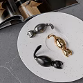 Black and Gold Curved Hooks on White Speckled Plate with Open Magazine and Gray Countertop