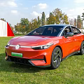 Volkswagen Electric Car Parked On Grass Near Red Barn And Trees
