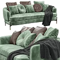 Green Velvet Two Seater Sofa With Decorative Pillows And Black Throw Blanket