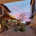 Traditional Courtyard Cafe With Thatched Roof Pebble Ground Green Plants Outdoor Seating Area Twilight