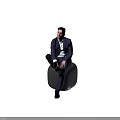 A Man In Navy Suit White Shirt Sitting On Gray Cylindrical Stool Brown Background