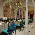Ornate Restaurant Interior With Colorful Patterned Walls Chandeliers White Columns And Blue Chairs