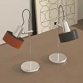 Two Modern Table Lamps With Orange Black Shades Silver Metal Poles On Wooden Table