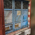 Weathered Blue Entrance Door With Decorative Patterns Striped Panels Bronze Plates And Red Frame