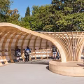 Curved Wooden Architectural Structure With Seating Area Where People Relax In Public Space