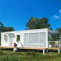 White Container House with Wooden Deck Green Plants Natural Surroundings by Water Under Blue Sky