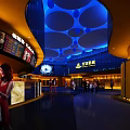 Modern Cinema Lobby With IMAX Sign And Shoppers Under Blue Lighting
