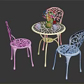 White Metal Outdoor Table With Intricate Cutout Chairs Orange Vase Blue Cups And Flower Decoration