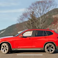 Red BMW SUV Exterior View Parked On Road With Building Background