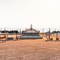 Vast Desert Landscape Featuring Traditional Building Trees And Vehicles Under Clear Sky