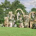 Outdoor Banquet Hall with Floral Decorations Arches and Grass Lawn Setting