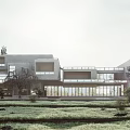 Modern Sales Office Building with Open Terrace and Glass Facade Surrounded by Trees and Lawn