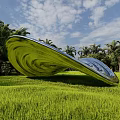 Silver Spiral Landscape Sculpture in Lush Green Park With Surrounding Trees and Grass