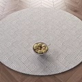 Round Rug with Geometric Pattern on Wooden Floor Featuring Bowl of Stones in Center
