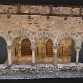 Cartoon Scene of Ancient Stone Arches with Carved Pillars and Wooden Doors in Medieval Courtyard