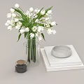 Clear Glass Vase With White Tulips Stack Of Books Gray Round Dish And Black Jar