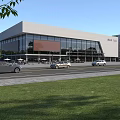 Modern Commercial Street With Glass Facade Buildings Parked Cars And Green Lawns