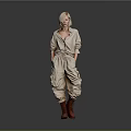 Blonde Woman in Beige Jumpsuit with Knee High Boots Standing Against Gray Background