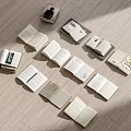 Multiple Open Books of Various Types Scattered On Light Colored Wooden Floor