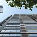 High Rise Residential Building With Multiple Windows Surrounded by Green Trees Under Clear Blue Sky