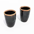 Two Black Cylindrical Ceramic Vessels with Brown Rimmed Accents on White Background