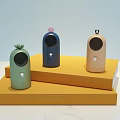Three Different Colored Small Daily Electrical Appliances With Decorative Tops On Yellow Display Stands