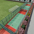 Outdoor Sports Fitness Space With Fenced Tennis Courts Green Red Surfaces Adjacent Soccer Field Flowering Plants