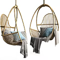 Stylish Rattan Hanging Chair with Blue and Gray Pillows and Cozy Blanket