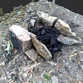 Simple Outdoor Stone Built Fireplace With Charcoal And Surrounding Dirt Leaves