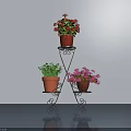 Potted Plants On Black Metal Three Tier Stand With Red Pink Flowers And Green Foliage