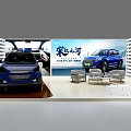 Modern Exhibition Booth Displaying Two Blue Cars With Backdrop And Chairs