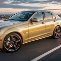 Golden Sedan Driving On Open Road With Scenic Sunset Sky Background