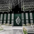 Elegant Banquet Hall Interior With Crystal Chandeliers Green Backdrop White Chairs And Flower Arrangements