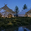 White Tents by Waterfront at Night With Greenery Fairy Lights Trees and Water Reflection