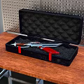 Knife In Black Case Placed On Wooden Table With Perforated Metal Background