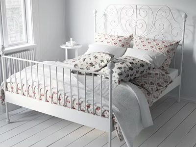 White Metal Bed With Decorative Headboard Floral Pillows Quilt And Bedside Table In White Bedroom 3d model