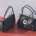 Black Handbags With Round Metal Clasp On Red Surface And Gray Wall Background
