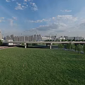 Modern Bridge Over River With Tall Buildings Green Grass And Blue Sky