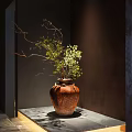 Rustic Terracotta Vase With Green Foliage And Dried Branches On Gray Tabletop Against Dark Walls