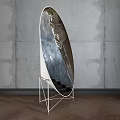 Silver Oval Reflective Metal Sculpture With White Metal Stand And Concrete Wall Wooden Floor