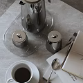 Elegant Stainless Steel Tea Set With White Cup Saucer And Magazines On Gray Table