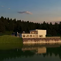 White Detached Villa Lakeside With Green Grass Trees Sunset Sky And Lake Reflection
