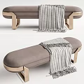 Gray Upholstered Ottoman With Gold Metal Legs And Striped Throw Blanket