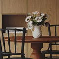 Wooden Desk With White Vase Light Pink Flowers Black Chairs And Books On Cabinet