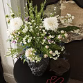 Black Textured Vase With White Purple Flowers On Dark Table Near Round Decorative Mirror