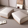 Two White Upholstered Footstools On Striped Rug With Open Book Vase And Wall Art