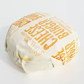 Fresh Tasty Cheeseburger Wrapped in Paper Packaging with Cheese Label