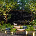 Modern Courtyard Garden With Waterfall Wall Trees Lush Plants Comfortable Chair And Warm Lighting