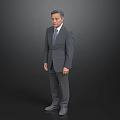 A Man Standing In Dark Background Wearing Gray Suit And Tie