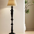 Elegant Black Floor Lamp With Decorative Column Design Against Beige Wall And Green Plant